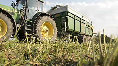Combine harvester with tractor trailer harvesting hay.