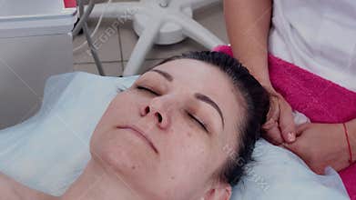 A woman lies on a couch in a cosmetologist's office before a procedure