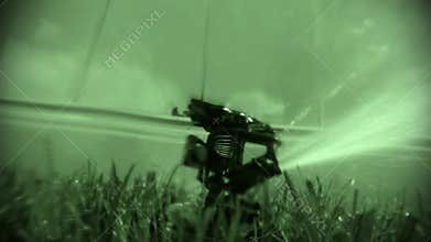 Night view oscillating lawn sprinkler watering grass