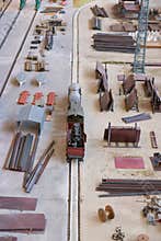 Small model train navigating through an industrial layout with various materials and structures