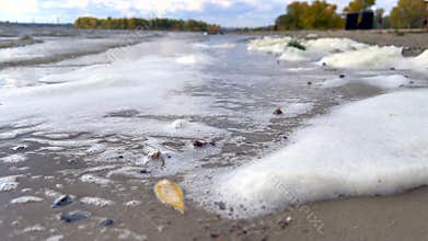Polluted water foaming on a riverbank shoreline