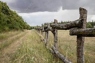 Rustic Wooden Fence on Countryside Meadow under Stormy Sky