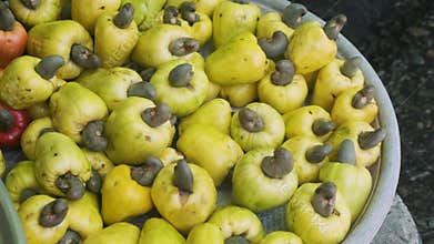 Pile of fresh cashew apples with attached cashew nuts on display at traditional food market in Phu Quoc, Vietnam