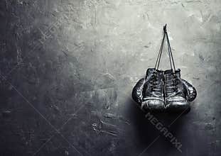 Old boxing gloves hang on nail on texture wall