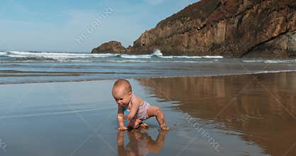 Baby crawling on wet sandy beach, close wide