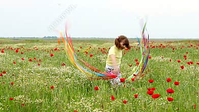 Little girl waving with colorful ribbons on meadow