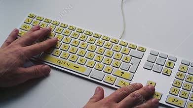Computer keyboard with braille font alphabet. Blind person is typing words, hands