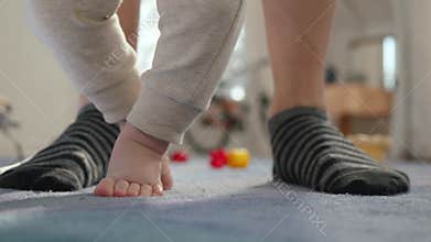 A Baby Taking Their First Steps with Loving Parent Support