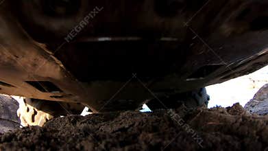 Off-road vehicle navigating through sandy terrain, showcasing the undercarriage and tire movement, capturing the dynamic action of