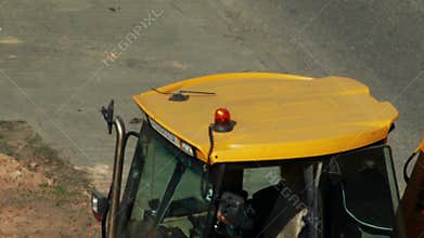 Orange beacon flashing on yellow roof of tractor loader, industry. Copy space for text, renovation work