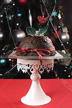 Beautiful Christmas table setting in front of Christmas Tree, featuring a classic plum pudding