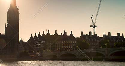 People and red buses crossing Westminster Bridge at sunset by Big Ben and the Houses of Parliament, London, England