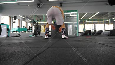Athletic man prepares for workout, transitioning from standing to crouching position, showcasing strength and agility in modern