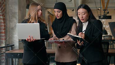 Business team work in international office three multiracial women discussing laptop papers datum planning budget