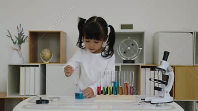 toddler girl scientist study using pipette dropping liquid with test tube and beaker.