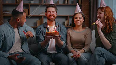 Four multiracial cheerful friends at home party congratulate birthday man laughing carefree smiling holding cake with