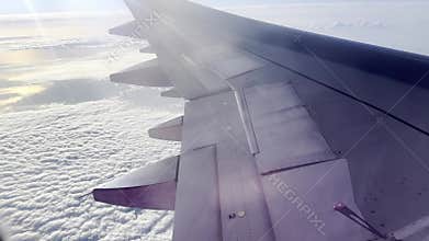 View from airplane window above the clouds on a bright