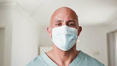 Focused Male Healthcare Worker in Scrubs and Surgical Mask Looks Directly at Camera