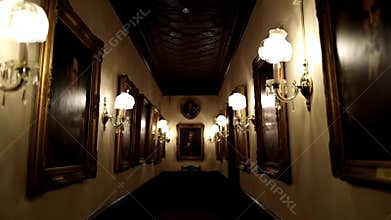 Dimly lit long hallway of an elegant estate filled with framed portraits