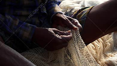Shivering hands of fishermen repairing the net.