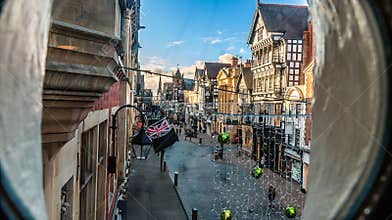 A view through a porthole window west up Eastgate Street in the city of Chester