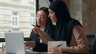 Two diversity business women girls team multiracial females businesswomen at table looking laptop talking Asian boss