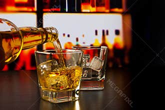Barman pouring whiskey in front of whiskey glass and bottles