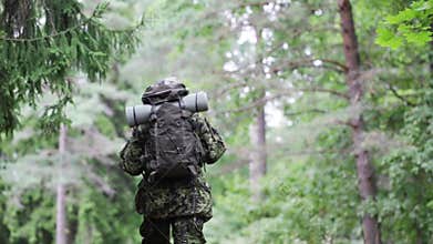 Young soldier with backpack in forest