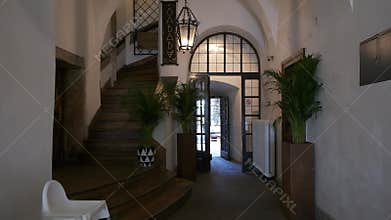 Interior hallway with a large wooden staircase and arched doorway leading to a bright entrance
