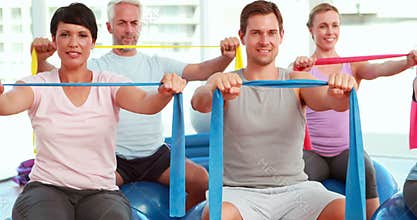 Group sitting on exercise balls stretching resistance bands