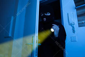 Thief holding flashlight while entering into house