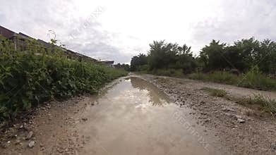 puddle along the diminishing perspective rural pathway into the rural countryside by the construction site.