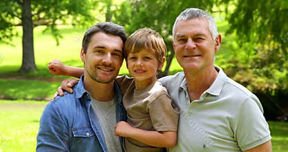 Three generations of men smiling at camera in the park
