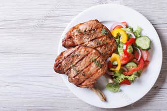 Pork meat grilled with fresh vegetable salad top view