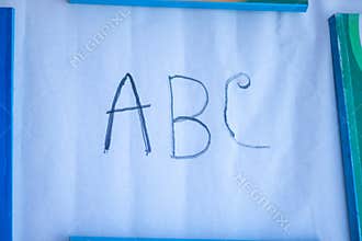 Handwritten abc letters on white paper with blue borders