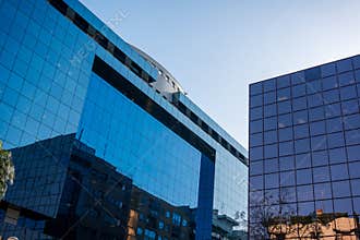 Modern glass office skyscrapers reflecting city buildings and sky