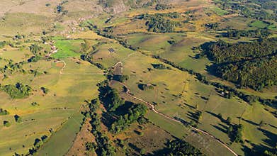 Drone aerial of Romanija farmlands with colorful fields and meadows forming patchwork landscape in Bosnia