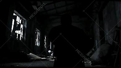 Silhouette of Man Standing in Dark Abandoned Warehouse