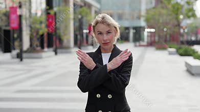 Portrait of woman manager shows Cancel gesture against downtown buildings