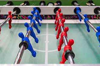 Close-up view of a foosball table, showcasing dynamic play between two teams in contrasting colors red and blue Perspective