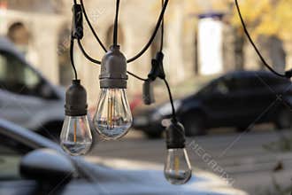 Hanging Decorative Light Bulbs with Urban Bokeh Background