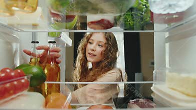 Young Happy Woman at Kitchen Opening Fridge Door and Taking Beer Bottle to Drink