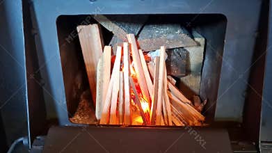 Lighting wood inside a metal stove using burning kindling