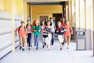 Group Of High School Students Running Along Corridor