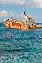 The Edro III, Pegeia, Cyprus - rusty shipwreck resting in clear turquoise sea near rocky breakwater offshore by shoreline