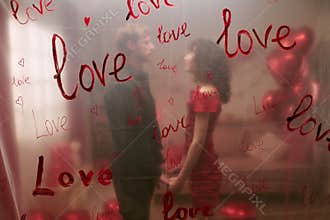 Young Couple Holding Hands Surrounded by Love Decorations Indoors