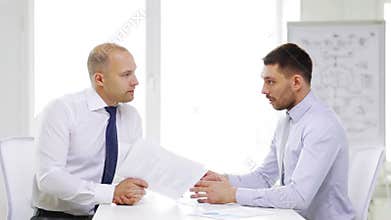 Two serious businessmen with charts in office