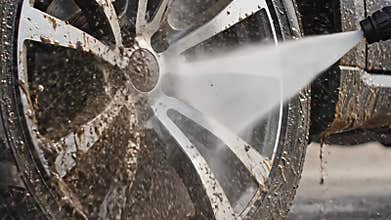 Dynamic water jets cleanse intricately designed car tires, showcasing a blend of artistry and technology in an urban setting