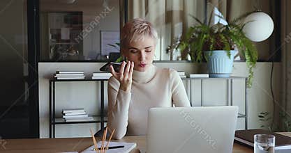 Businesswoman recording voice message using virtual assistant on smartphone