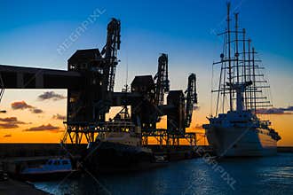 Old sailer five-master sailer in front of three old cranes in evening backlight with great evening skies, Barbados, Carribean Sea
